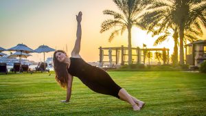 A picture of Miriam Vadillo a certified Pilates Instructor, performing a side plank at a dubai beach